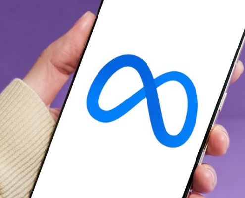 purple background with arm and hand in view holding a smart phone with the Meta logo on the screen