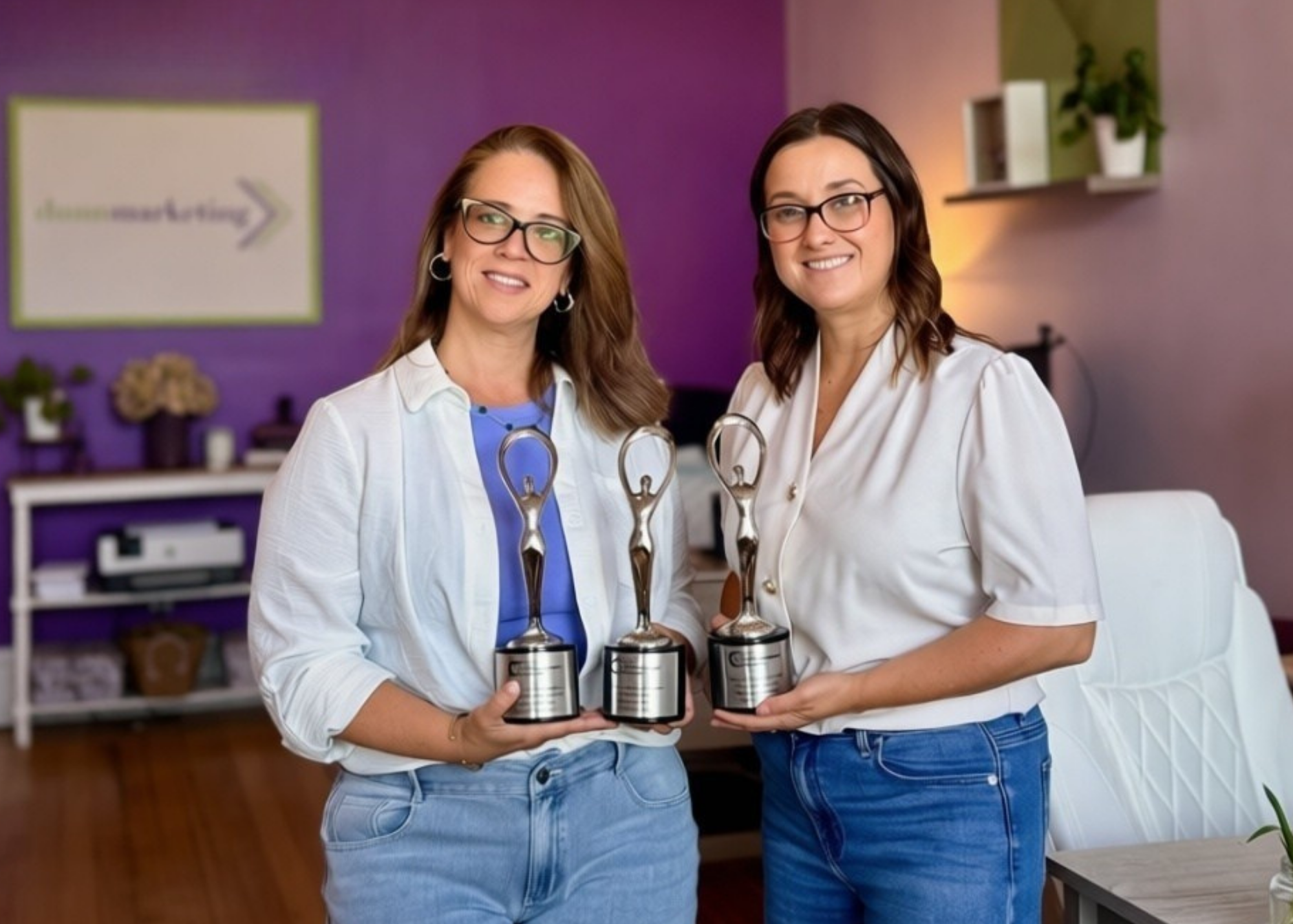 Dunn Marketing leadership including CEO & Brand Strategist Laura Dunn (left) and VP Client Services Marci Seney (right) holding the agency's 3 Communicator Award statues for 2026 at their Danielson office