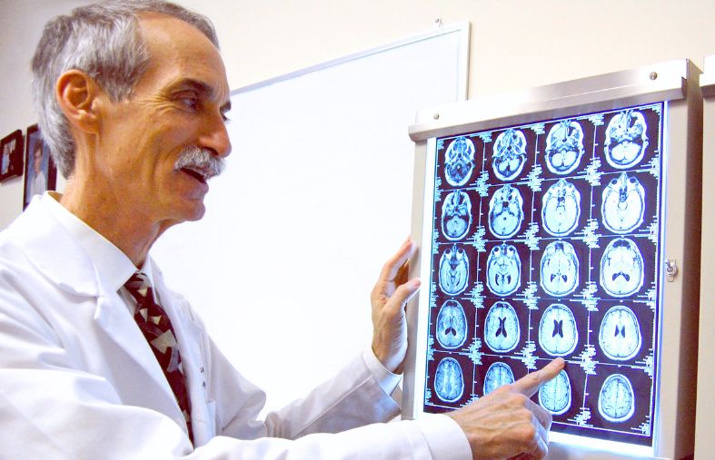 a doctor examining and pointing to brain imaging scans